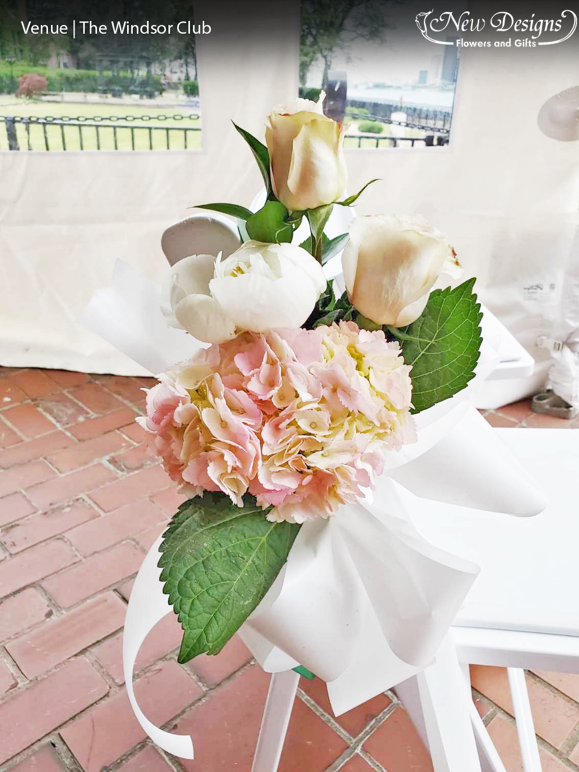 A floral installment, along the inner chairs of a wedding aisle, of Dusty Pink Hydrangeas, White Peonies, and Nude Roses, Tied with a White Satin Bow